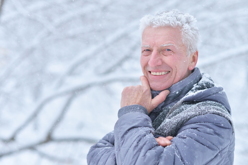 Senior man smiling in winter, outside in snow