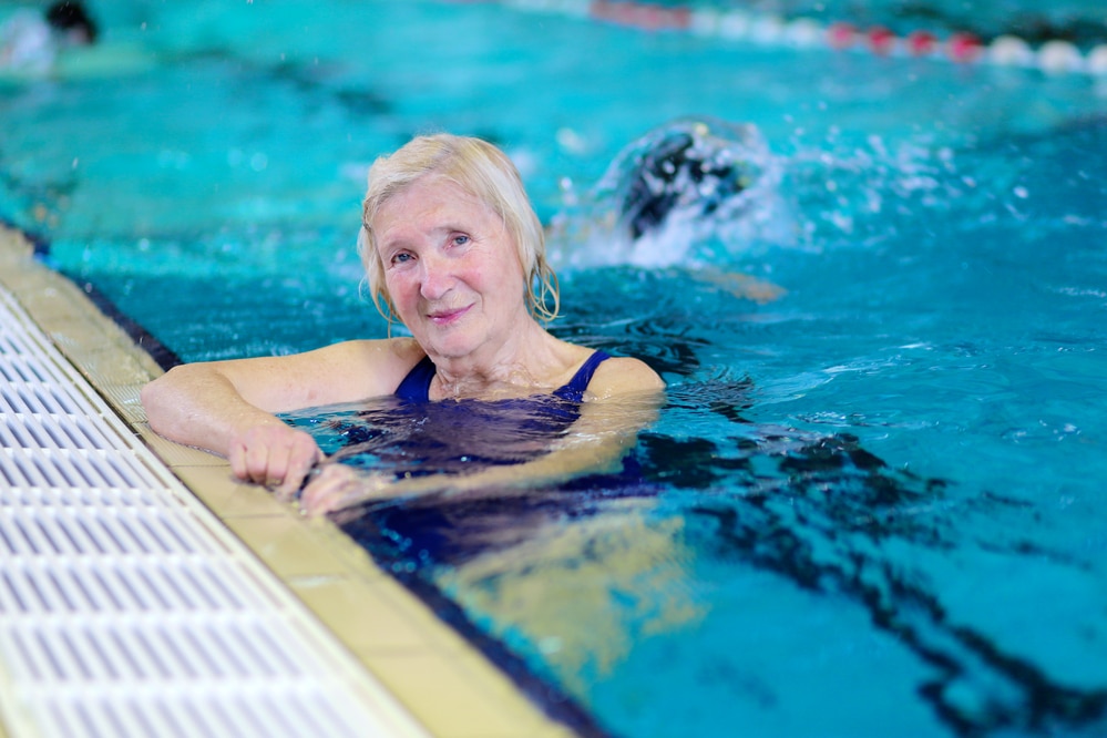 Senior woman hanging on to side of public pool