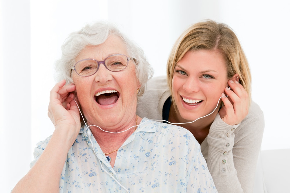 Smiling young woman and senior woman listening to music with earbuds