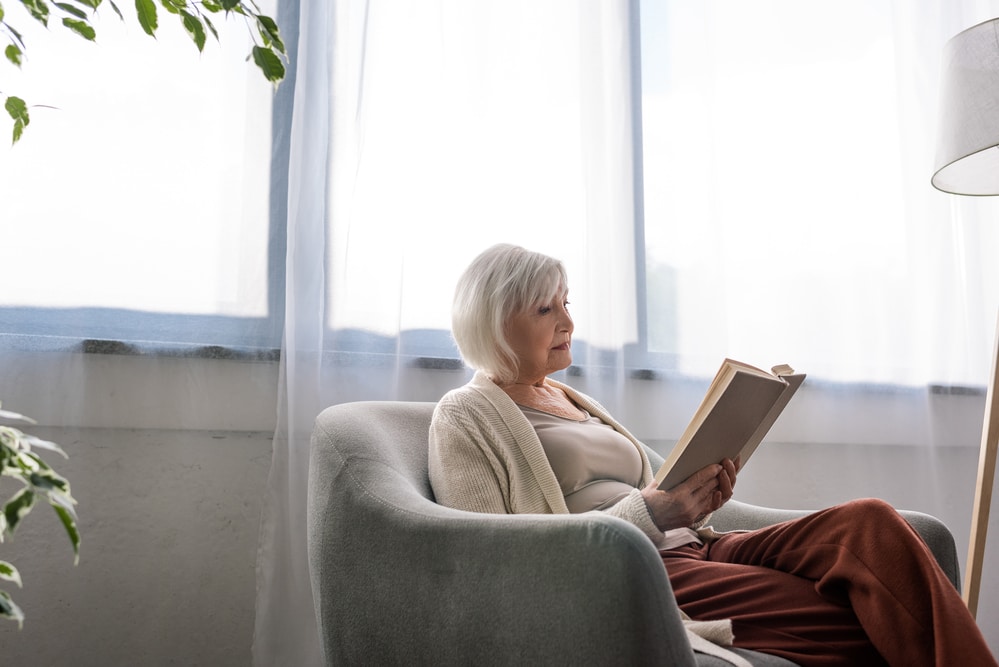 senior woman reading in chair indoors