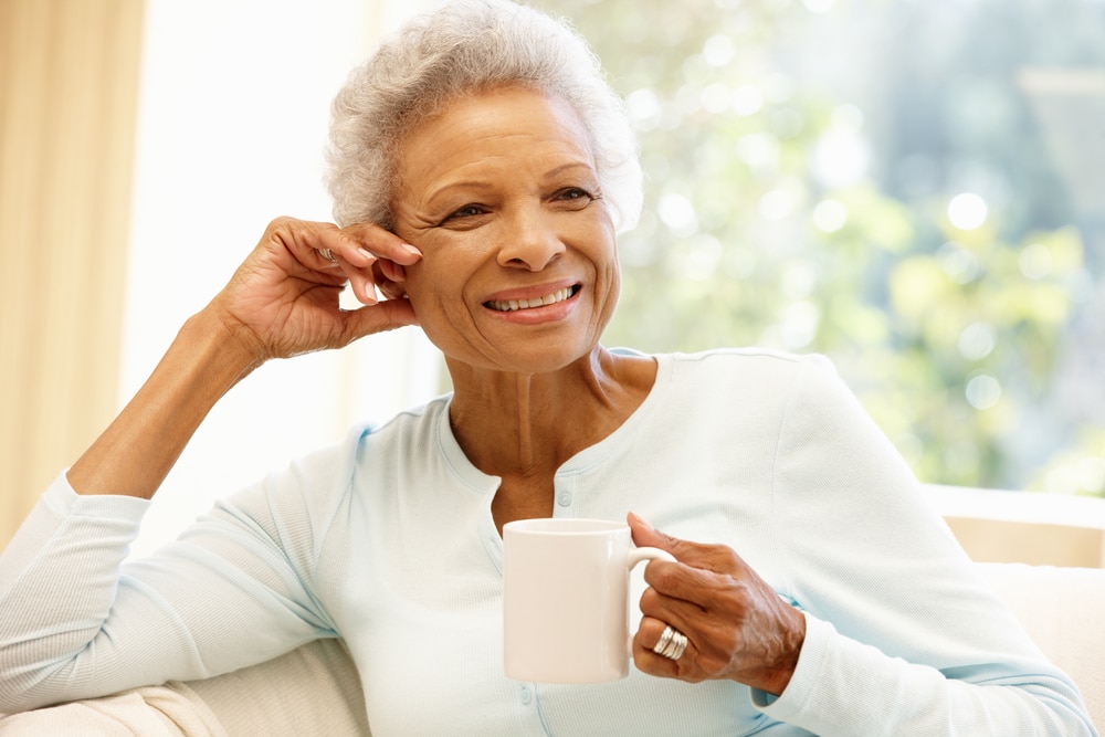 Smiling senior woman drinking coffee near window