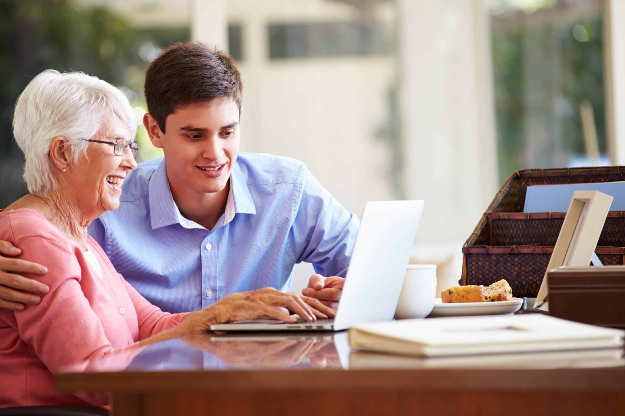Senior woman and young man looking at laptop and smiling