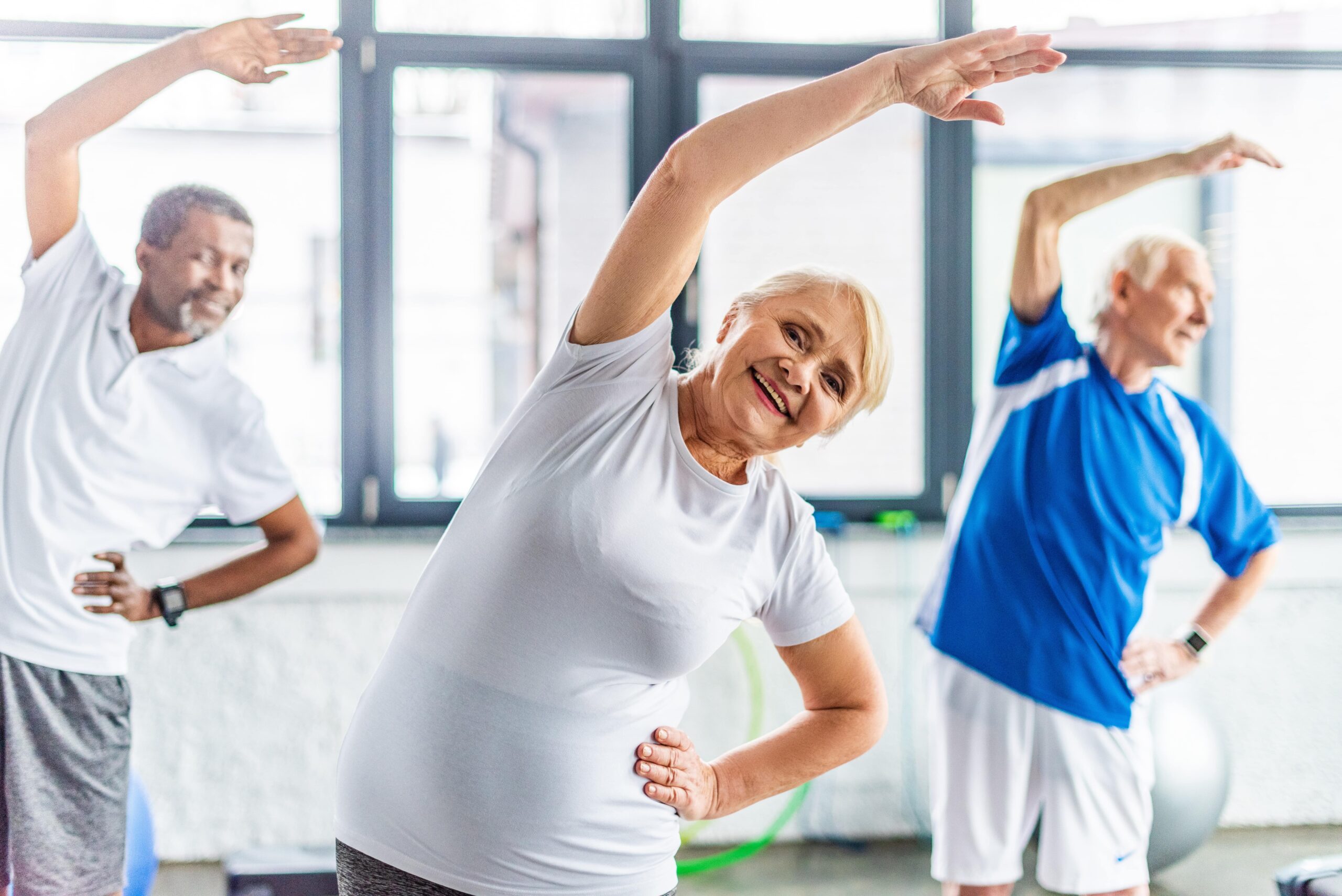 Senior woman smiling and stretching during exercise class